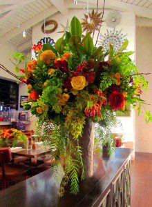 Fig, Santa Monica: Restaurant floral arrangement. Pepper berry, spray roses, gloriosa lily, magnolia, maidenhair fern, figs, celosia. Yellow, orange, red flowers.