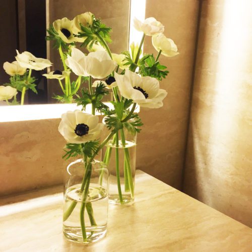 White anemones rest in glass bud vases on a bathroom table at a Hollywood event.